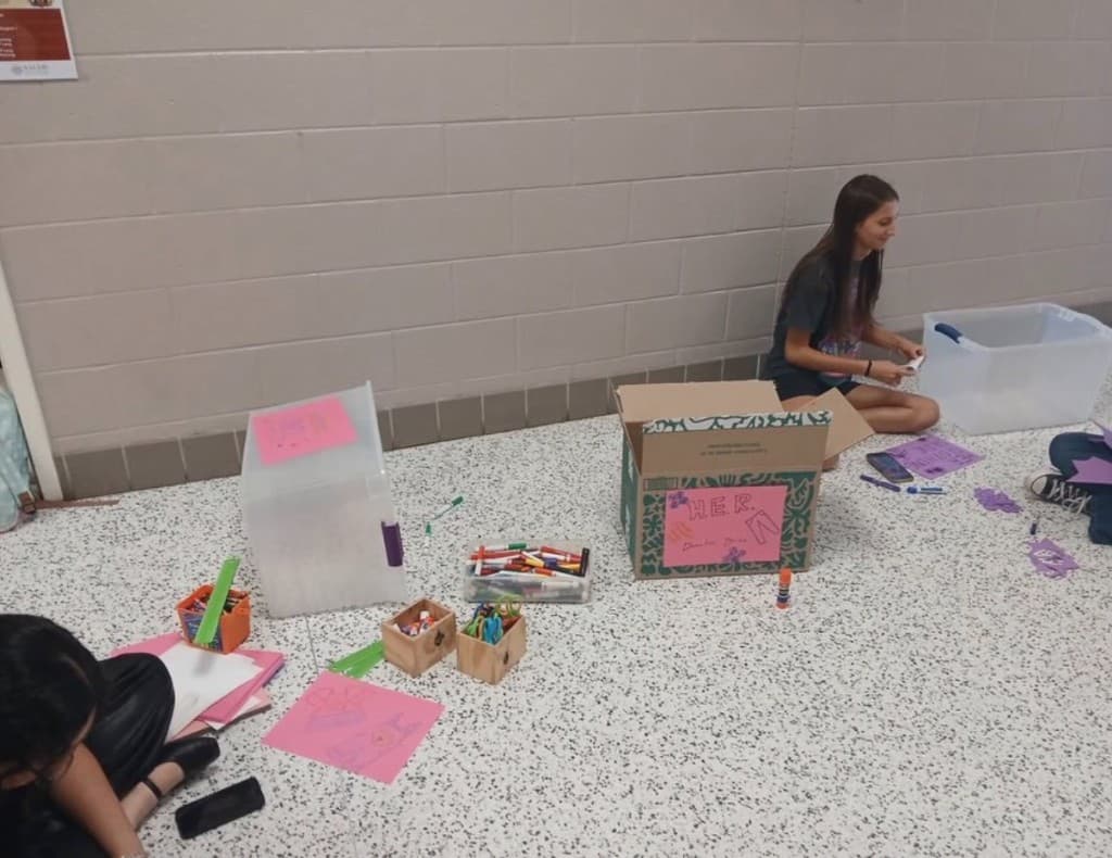 Classroom whiteboard promoting H.E.R. and women to learn about